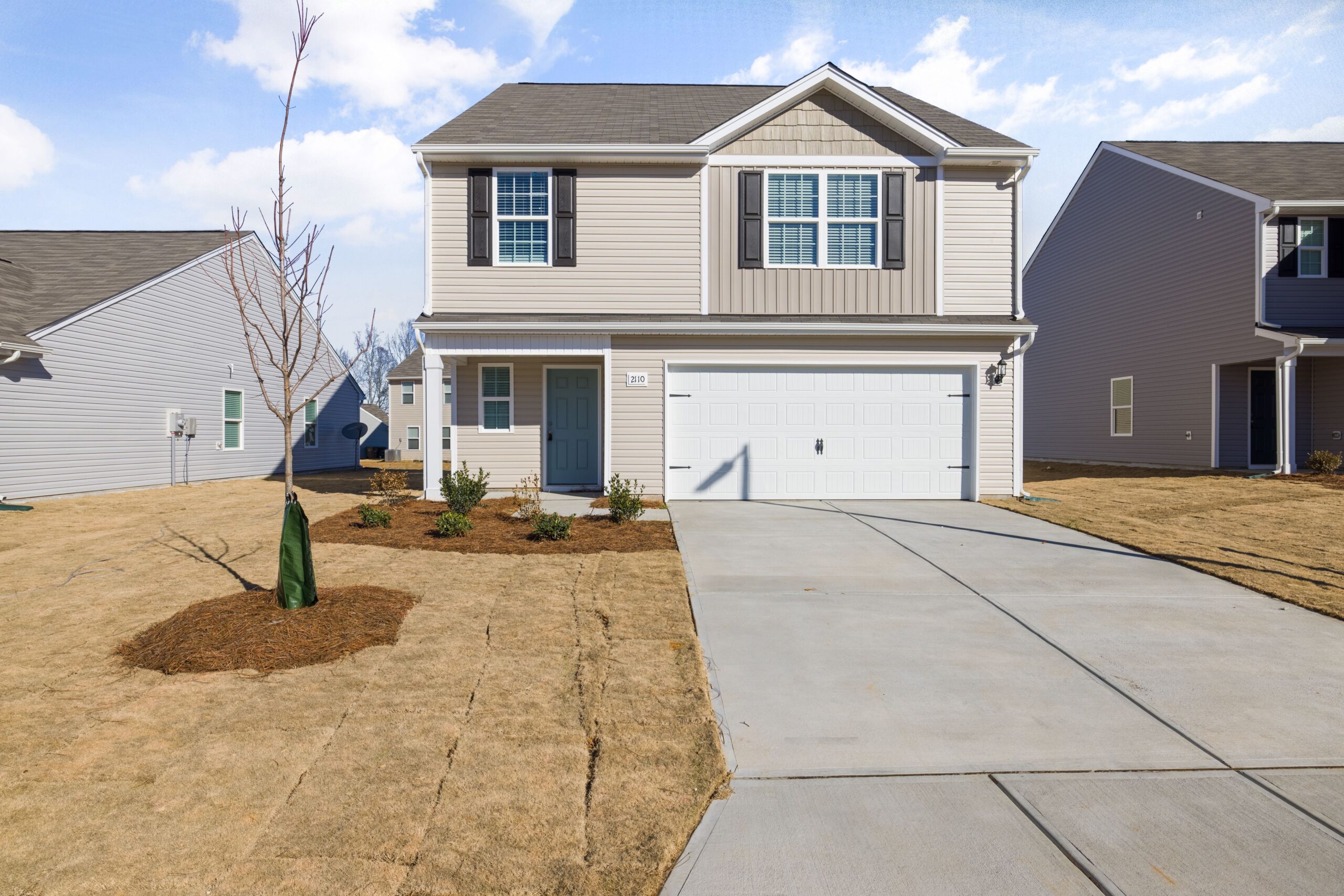 A contemporary suburban house with a spacious driveway and garage under a clear sky.