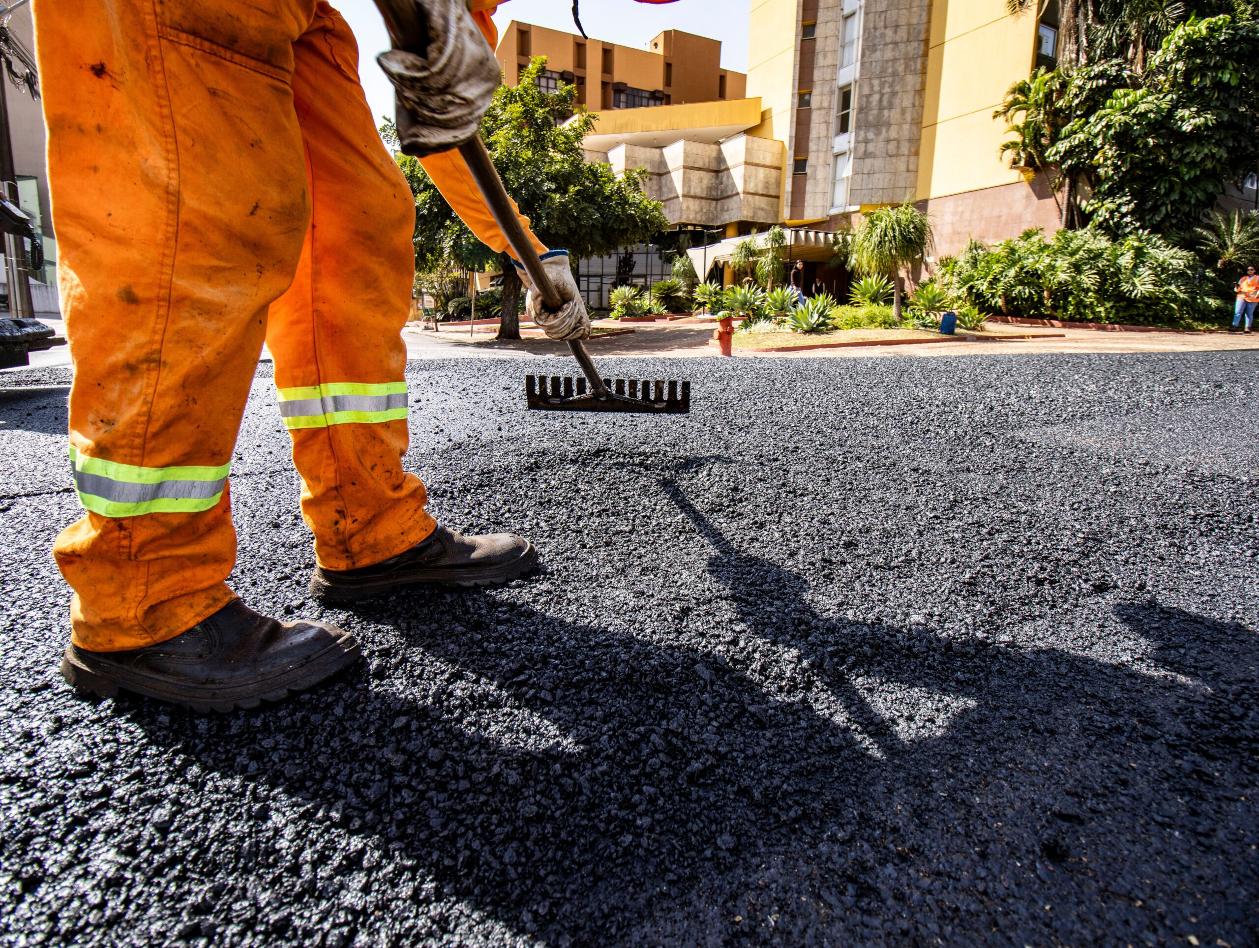 Worker in orange gear paving a road in Londrina city during daytime.